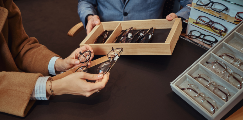 An optician helping a patient choose a new pair of glasses at the opticians.