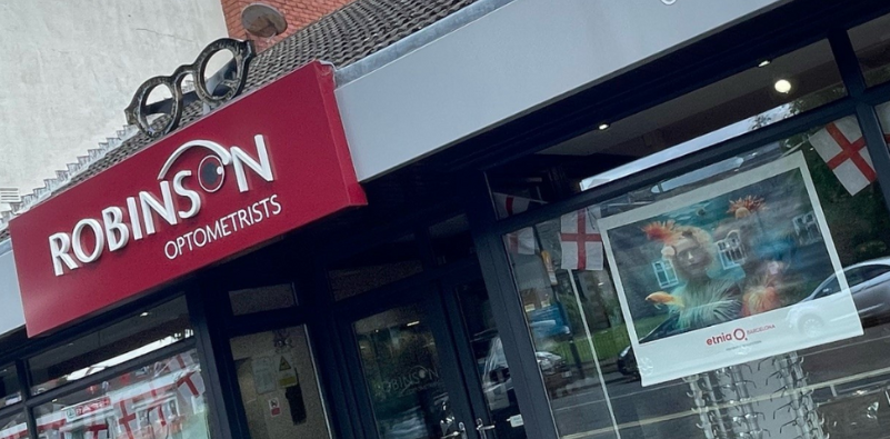 A photo of the outside of Robinson Optometrists, focusing on the signage outside the building, featuring eyewear window displays.