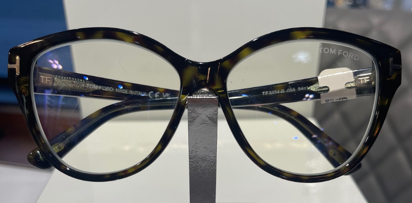 A close-up of a pair of mottled Tom Ford glasses on a metal stand.