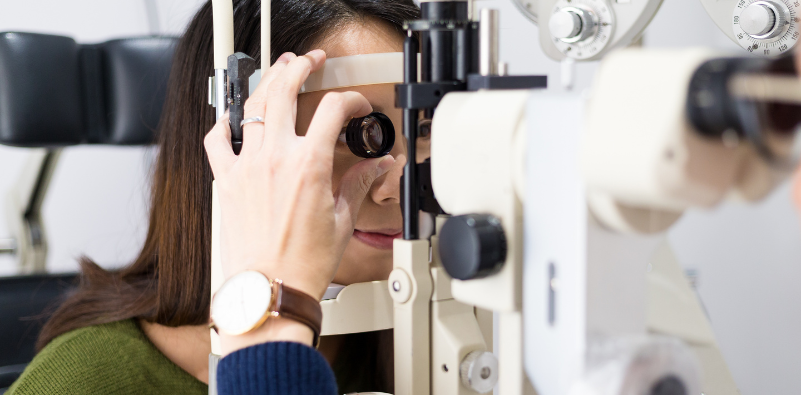 An optometrist looking at a patient’s eye during an eye exam