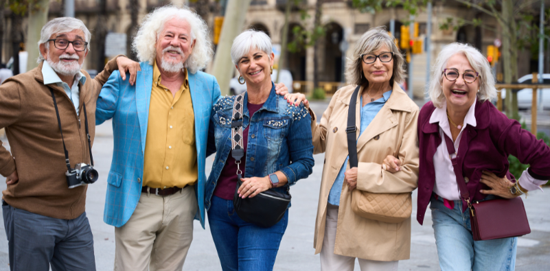 A group of older adults smiling together on a city street.