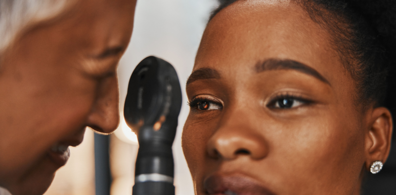 An optometrist examining a patient’s eye with a retinoscope.
