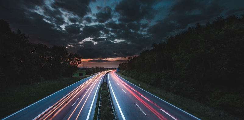 A long exposure of car headlights and taillights on a motorway at night.