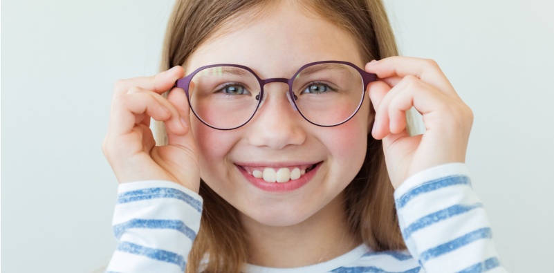 Young girl holding her glasses on her face while smiling