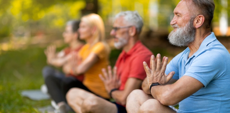 Men and women taking part in yoga on the grass outdoors