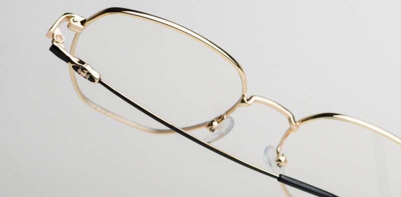 Minimalist gold glasses on a neutral background.