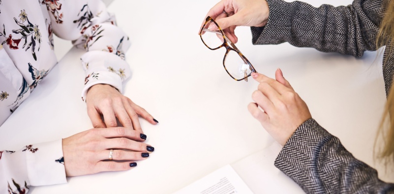 An optician assisting a patient with choosing a new pair of glasses and lenses.