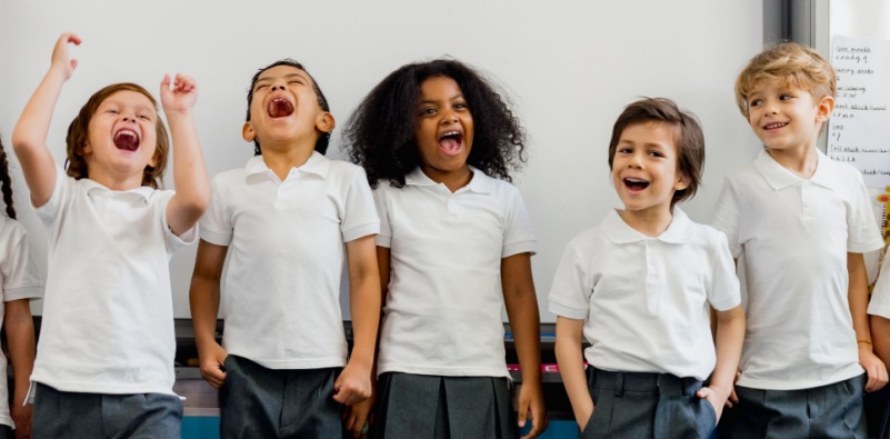 A diverse group of school children having fun in front of the whiteboard in a school classroom.
