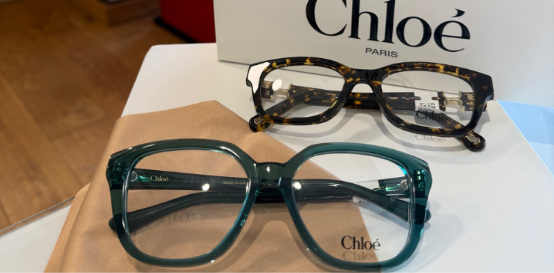 Two pairs of Chloé glasses—one teal and one tortoiseshell—displayed on a retail stand.