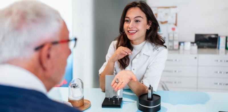 A patient discussing hearing aids with an audiologist in a clinical environment.
